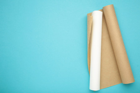 Rolls of white and brown baking paper on blue background. Top view