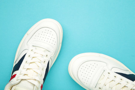 White sneakers, trainers on blue background. Unisex casual sports shoes.