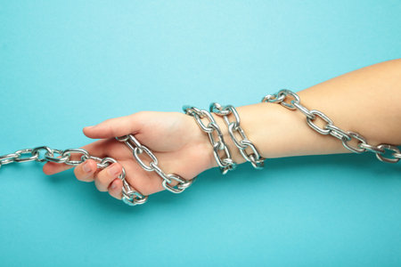 Hands are chained in chains on blue background. Top viewの写真素材