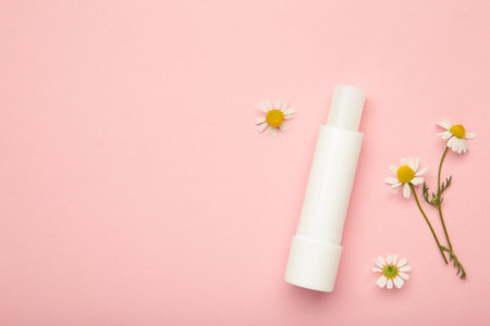 Lip balms and chamomile flowers on pink background. Top viewの写真素材