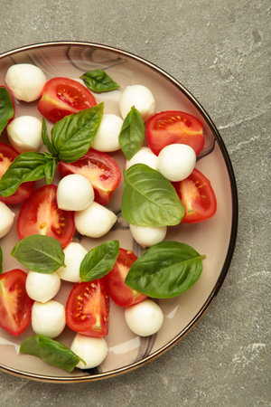 Italian Caprese salad with cherry tomatoes, mozzarella, basil on plate on gray background. Top viewの写真素材