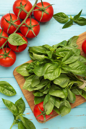 Fresh cherry tomatoes with basil leaves on blue wooden background. Top viewの写真素材