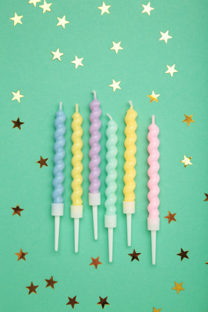 Candles with gold stars on mint background. Top view
