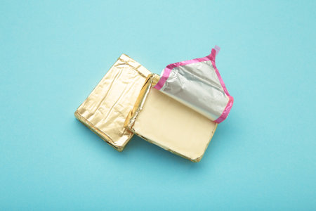 Processed cheese in foil on blue background. Top view