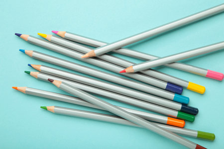 Many colorful pencils on blue background. Top view