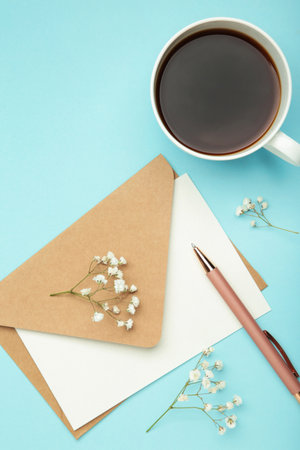Composition with craft envelope, cup of coffee and gypsophila on blue background. Top viewの写真素材