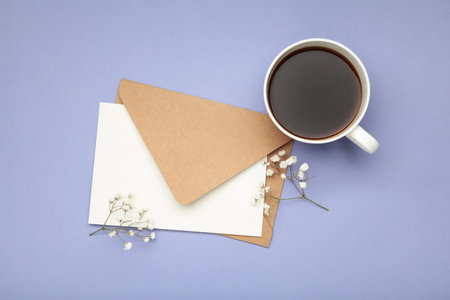 Composition with craft envelope, cup of coffee and gypsophila on purple background. Top viewの写真素材