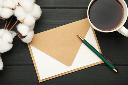 Composition with craft envelope and cotton branch on black wooden background. Top viewの写真素材
