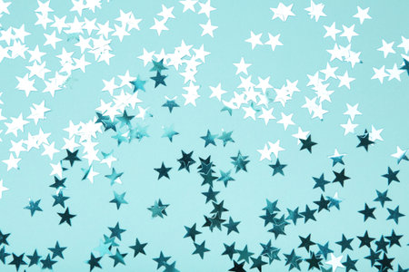 Blue glitter stars on blue background. Top view