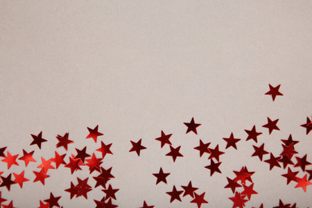 Red glitter stars on gray background. Top view