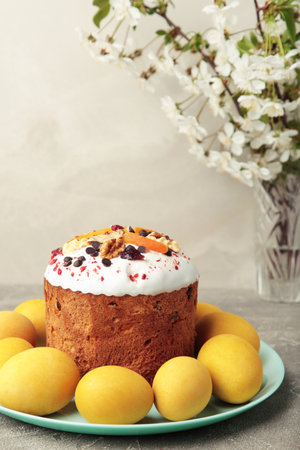 Traditional easter cakes with colorful sprinkles, with eggs, and spring flowers on gray concrete
