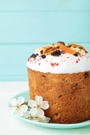 Traditional easter cakes with colorful sprinkles, with eggs and spring flowers on blue background....