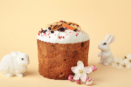 Traditional easter cakes with colorful sprinkles, bunny figurine, and spring flowers on beige background. Top viewの写真素材