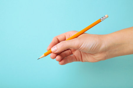 Woman holding pencil on blue background, top viewの写真素材