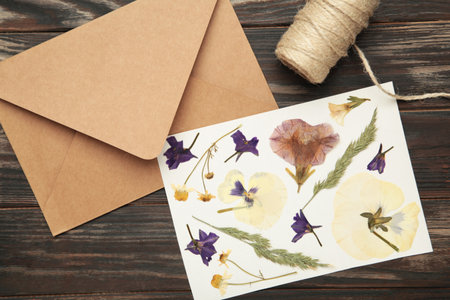 Pressed and dried flowers with twine on brown wooden background.