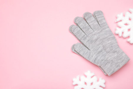 Warm woolen knitted gloves on pink background. Space for textの写真素材