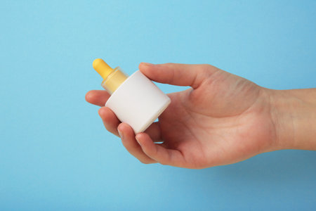 Beauty cosmetic skincare oil in bottle on blue background. Elegant mockup for skincare, serum, or beauty branding presentations. Top viewの写真素材