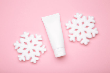 Winter skin care concept. Cosmetic moisturizer cream and snowflakes on pink background. Top viewの写真素材