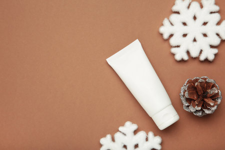 Winter skin care concept. Cosmetic moisturizer cream and snowflakes on brown background. Top viewの写真素材