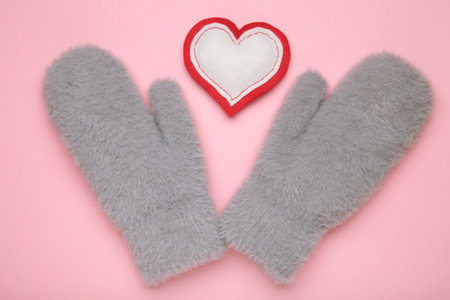 Warm gray mittens with heart on pink background. Top viewの写真素材