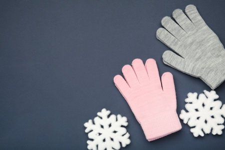 Warm woolen knitted gloves with white snowflakes on dark blue background. Space for textの写真素材