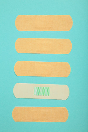 Medical sticking plasters on blue background. First aid item. Vertical photoの写真素材