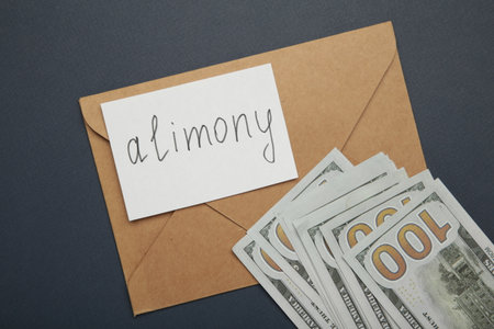 Envelope with word Alimony and money on dark blue background. Top viewの写真素材