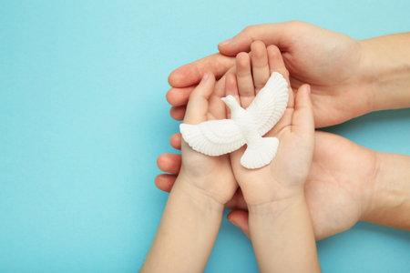 Hands of family with dove on blue background. Mother and child. Top viewの写真素材