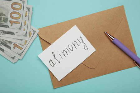 Envelope with word Alimony and money on blue background. Top viewの写真素材