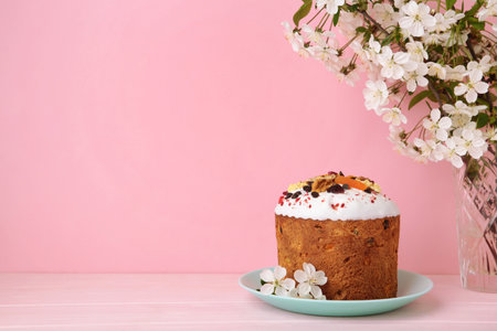 Traditional easter cakes with colorful sprinkles, with a bunny figurine, and spring flowers on pink....