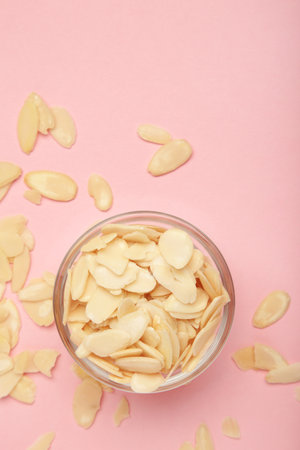 Fresh almond flakes in bowl on pink background, closeup. Top viewの写真素材