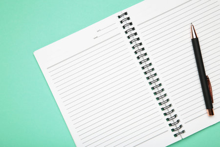 Open notepad and pen on mint background. Space for writing. Top view