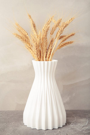 Spikelets of wheat in a vase on light background. Vertical photoの写真素材