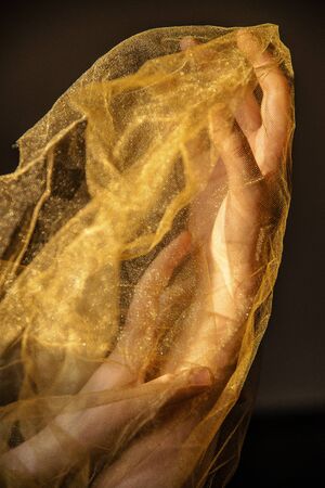 Hands in a golden cloth on a black backgroundの写真素材