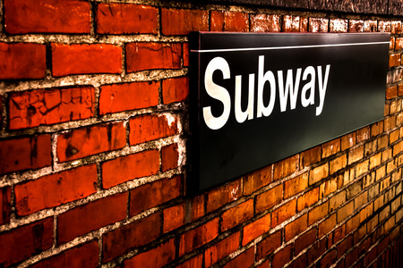 Subway sign on  red brick wall at night in Manhattan, New Yorkの写真素材