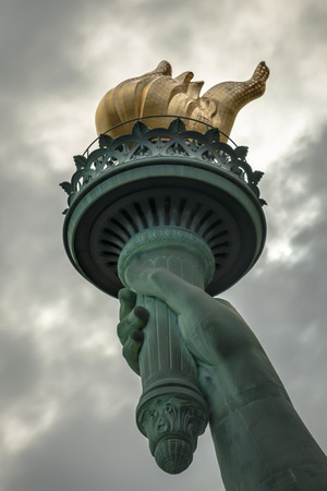 Closeup of the torch of Lady Liberty on a cloudy dayの写真素材