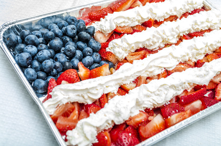 Whip Cream, strawberries and blueberries combined to look like the american flag and placed in a aluminium tray  for a 4th of july themed partyの写真素材
