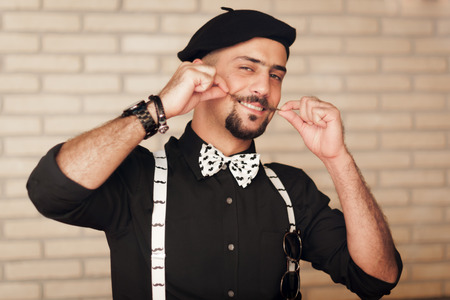 Funny face stylish hipster man twirling handlebar mustache with a playful attitude and a smile while...