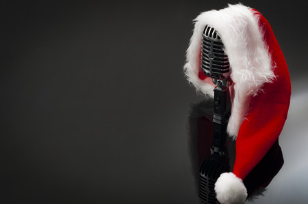 Carols and Christmas music concept with a microphone wearing a santa hat with copy spaceの写真素材