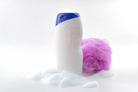 Personal hygiene, daily routine and body care toiletries concept theme with a bottle of shower gel soaked in water drops, bubbles made by soap foam and pink shower sponge isolated on white backgroundの写真素材