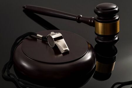 Whistleblower protection law and freedom of information legislation conceptual idea with metal whistle and wooden judge gavel on dark backgroundの写真素材