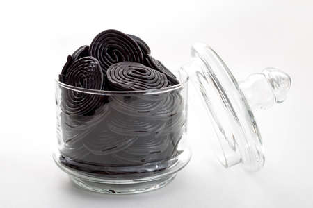 Black liquorice spirals, chewy candy and delicious dessert concept with licorice wheels which are flavoured with the extract of the root of the Glycyrrhiza glabra plant, in a clear glass jarの写真素材