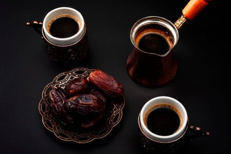 Middle eastern hospitality, dried fruit and traditional deserts concept theme with coffee pot, small cups and dates isolated on black backgroundの写真素材