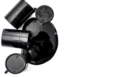 Environmental pollution, fossil fuel production and greenhouse gas concept with oil barrels and black pool of toxic petroleum spilled leaking from a barrel isolated on white background with copy spaceの写真素材