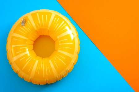 Summer vacation and safety equipment for swimming with a life buoy isolated on an orange and blue minimalist background with copy spaceの写真素材
