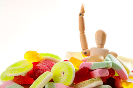 Sugar addiction, insulin resistance, unhealthy diet and November 14 is diabetes awareness day concept with a puppet drowning in sugar cubes isolated on white background and copy space for textの写真素材