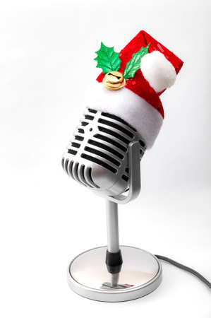 Christmas carols and winter sogs concept with a vintage metallic chrome microphone wearing a santa claus hat isolated on white background. Spreading the holiday cheer through musicの写真素材