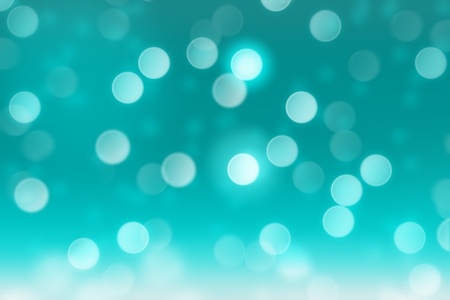 Falling snow on teal background with blurred circle bokeh, abstract backgroundの写真素材