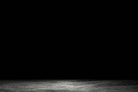 Light shining down on dirt gray cement floor in dark room with copy space, abstract backgroundの写真素材