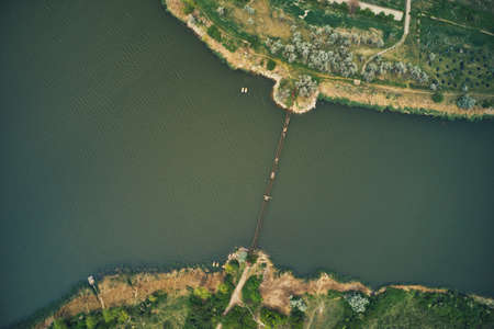 Aerial view of an old and broken bridge connecting one river bank to another